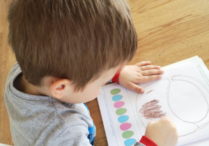 dziecko koloruje w książce koszyczek brązową kredką